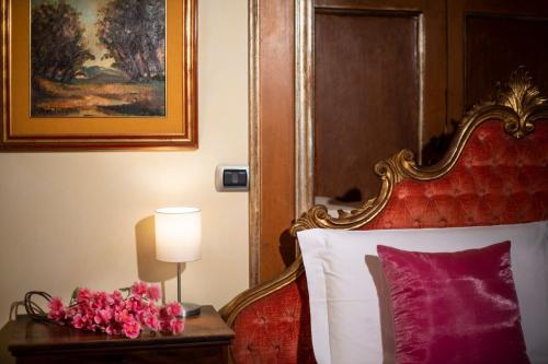 a bedroom with a bed and a table with flowers on it at Gran Suite Piazza Maggiore - T&T communications in Bologna