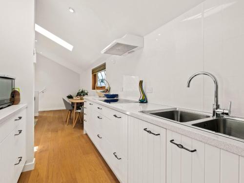 a kitchen with white cabinets and a stainless steel sink at The Loft at Sicilian in Queenstown