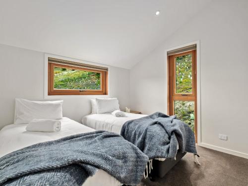 two beds in a white room with two windows at The Loft at Sicilian in Queenstown
