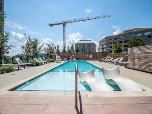 a swimming pool with white chairs and a crane at Bluebird Suites at Reston Town Center in Reston