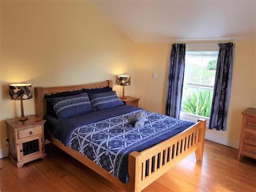 a bedroom with a bed with a blue comforter and a window at Endless Summer Lodge in Ahipara