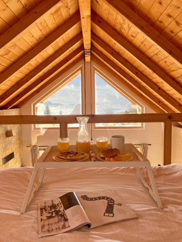 a tray of food on a bed with two glasses of orange juice at Planinska Koliba Exclusive in Sekulić 