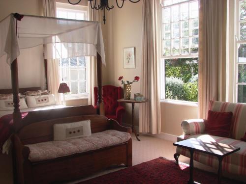 a living room with a bed and a couch and windows at Die Waenhuis Guest House in George