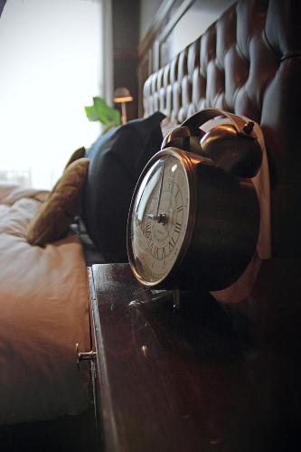 a clock sitting on a table next to a bed at Vinnhaus in Puerto Natales