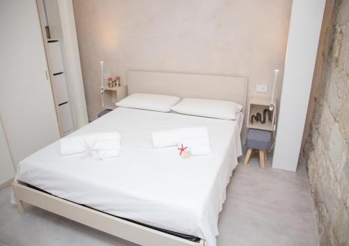 a bedroom with a white bed with two glasses on it at U scrusciu du mari - Casuzze SeaSound Holidays in Marina di Ragusa