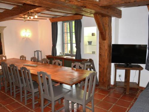 a dining room with a wooden table and a flat screen tv at Vintage Farmhouse with Garden Roofed Terrace BBQ in Gouvy