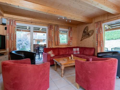 a living room with a red couch and chairs at Wooden chalet in Stadl an der Mur with sauna in Stadl an der Mur