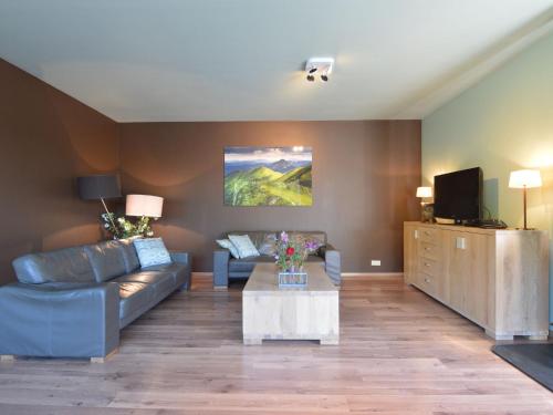 sala de estar con sofá y TV en Villa with infrared sauna located near golf course, en Durbuy