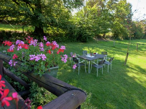 a table and chairs in a yard with flowers at Open wooden chalet built against a hill in Francorchamps