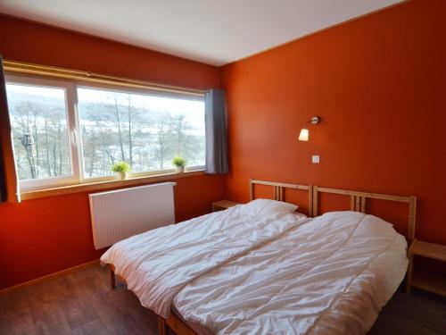 a bed in a room with orange walls and a window at Lovely modern cottage with sauna bubble baths in Grand Coo