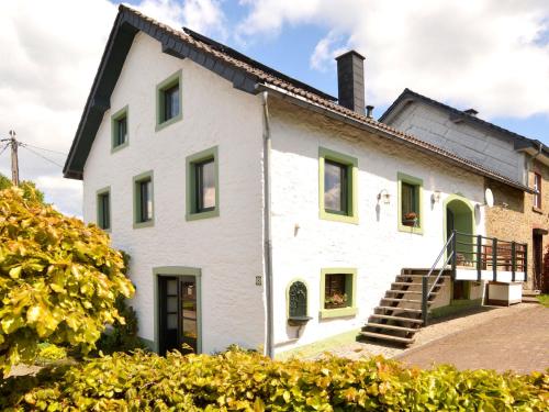 uma grande casa branca com janelas verdes e escadas em Lovely Holiday Home in B tgenbach by the Lake em Bütgenbach