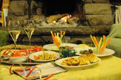 una tavola con piatti di cibo e bicchieri di vino di Hotel 2 Camini a Baselga di Pinè