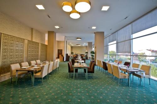 a dining room with tables and chairs and windows at North Point Hotel in Denizli