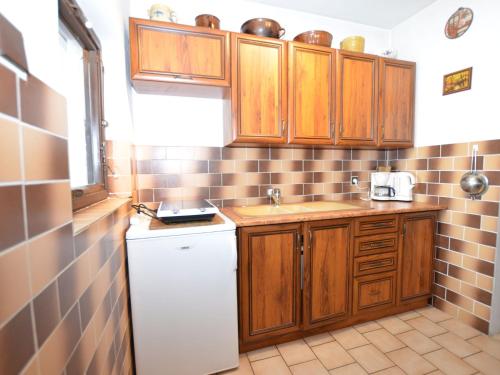 cocina con armarios de madera y nevera blanca en small holiday home at the edge of the forest, en Malá Skála