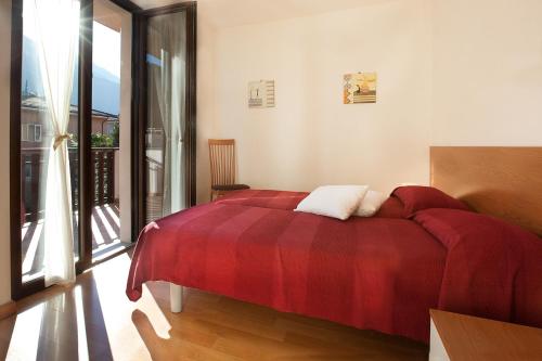 1 dormitorio con cama roja y balcón en Villetta Martinelli, en Nago-Torbole