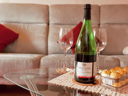 uma garrafa de vinho sentada numa mesa com dois copos de vinho em Apartment near the Nurburgring with terrace em Hillesheim