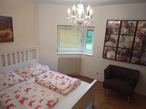 a bedroom with two beds and a chandelier and a chair at Casa Magnolia Vienna in Leopoldsdorf