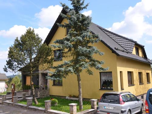 een geel huis met een auto ervoor geparkeerd bij Cosy apartment in Frauenwald near forest in Frauenwald