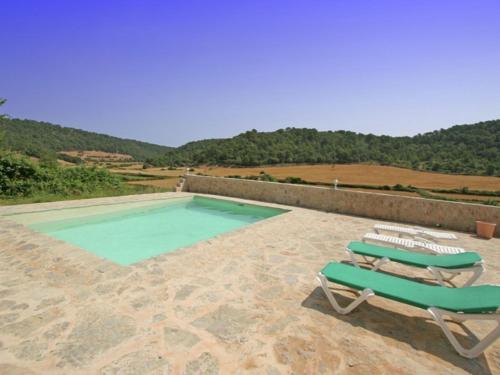 a swimming pool with two lounge chairs and a swimming poolvisor at Belvilla by OYO Canyar Enzell in Es Mercadal