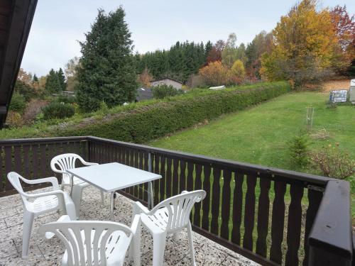 Appealing holiday home in Altenfeld with terrace في Altenfeld: فناء مع كراسي بيضاء وطاولة على شرفة