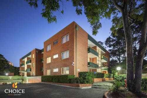 a brick building with a tree in front of it at APX Parramatta in Sydney
