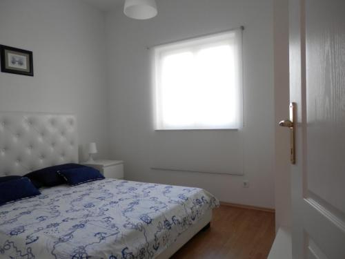 a white bedroom with a bed and a window at Apartments Nautica II in Novigrad Istria