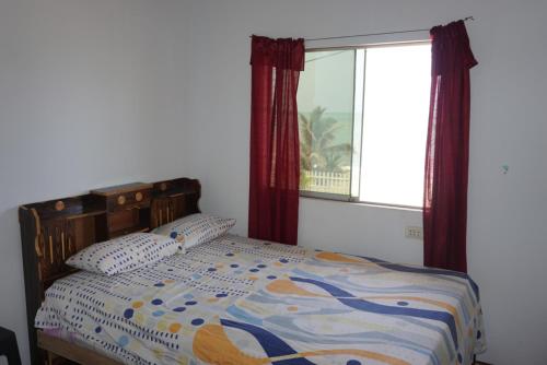 a bedroom with a bed with a window and a bedspread at Hostel Paqaryi in Zorritos