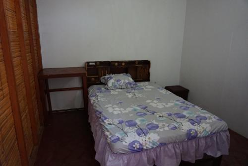 a bedroom with a bed with a comforter on it at Hostel Paqaryi in Zorritos
