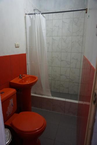a bathroom with a red toilet and a shower at Hostel Paqaryi in Zorritos
