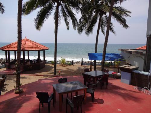 a patio with tables and chairs and the beach at Samsara Harmony Beach Resort in Varkala