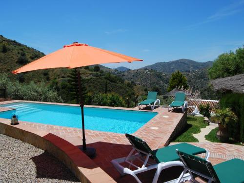 una piscina con sombrilla y sillas de color naranja en Belvilla by OYO Cortijo Ricardo en Acebuchal