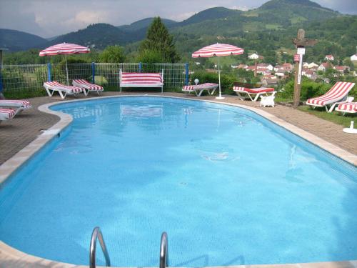 une grande piscine bleue avec des chaises et des parasols dans l'établissement Tidy chalet with dishwasher, in the High Vosges, à Le Ménil