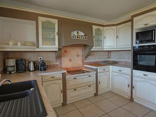 une grande cuisine avec des armoires et des appareils blancs dans l'établissement Villa in Vidauban with Heated Pool near Beaches, à Vidauban