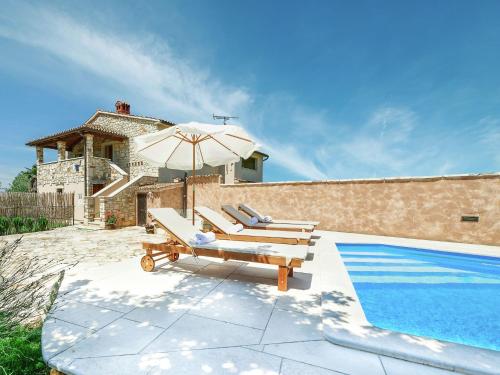 a pool with two lounge chairs and an umbrella next to a house at Modern Holiday Home in Porec with Swimming Pool in Nova Vas