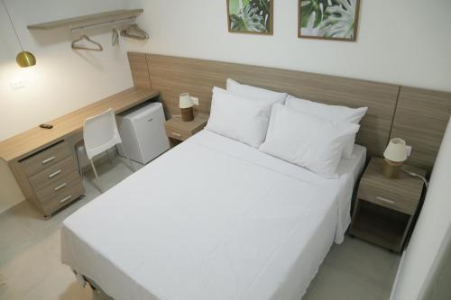 a bedroom with a large white bed and a desk at Flats Angatu Porto de Galinhas PE in Porto De Galinhas