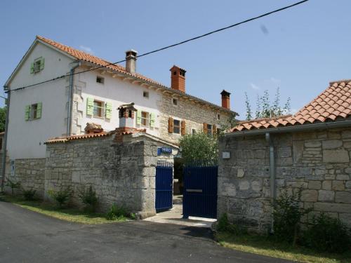 een wit huis met een stenen muur naast een gebouw bij Traditional villa with private pool in Peresiji