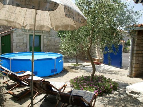 een groep stoelen en een parasol naast een zwembad bij Traditional villa with private pool in Peresiji