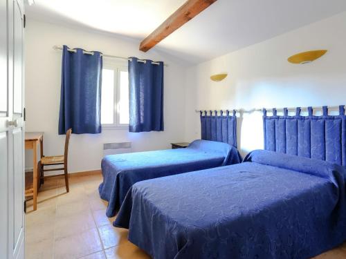 two beds in a room with blue curtains at Amazing holiday home in Bormes les Mimosas with pool in Bormes-les-Mimosas