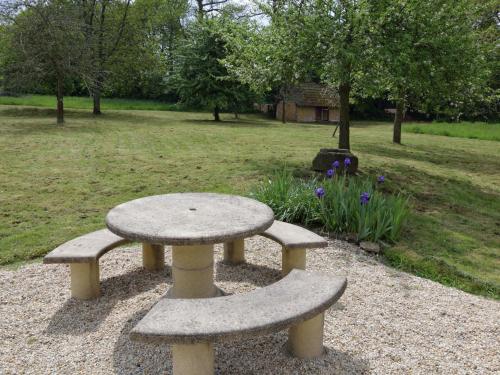 a stone bench and a table in a park at Pleasant holiday home with garden in Isigny-le-Buat
