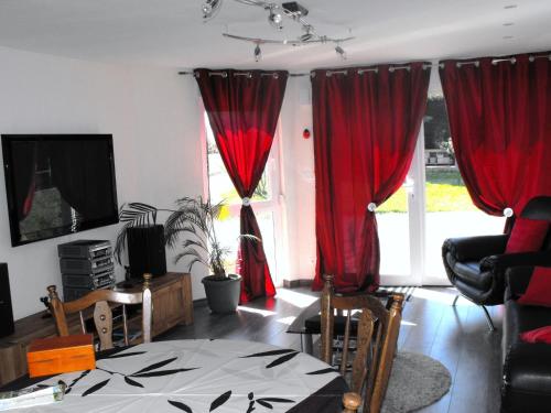 - un salon avec des rideaux rouges, une table et des chaises dans l'établissement Gite in Vosges with Pool and Hiking Trails, à Phalsbourg