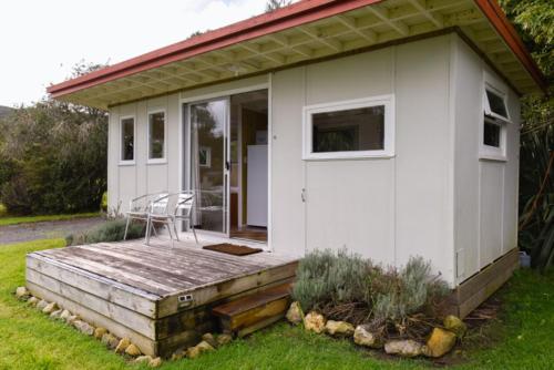 a white tiny house with a wooden deck at Russell-Orongo Bay Holiday Park in Russell