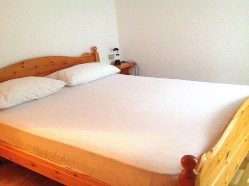 a bedroom with a wooden bed with two pillows at Lovely Chalet in Pozza di Fassa with Garden in Pozza di Fassa