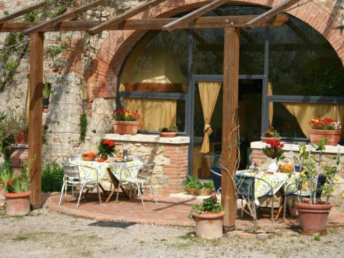 a patio with tables and chairs under a wooden pergola at Belvilla by OYO Villa Rapolano in Rapolano Terme