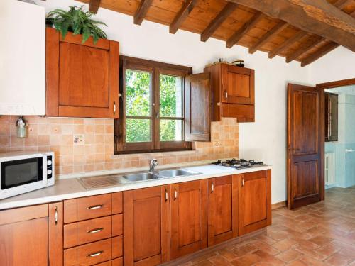Kuchnia z drewnianymi szafkami, zlewem i kuchenką mikrofalową w obiekcie Holiday Home in Umbria with Pool and Views w mieście San Secondo