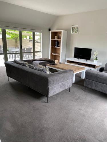 a living room with a large couch and a table at Home By Hagley Park in Christchurch