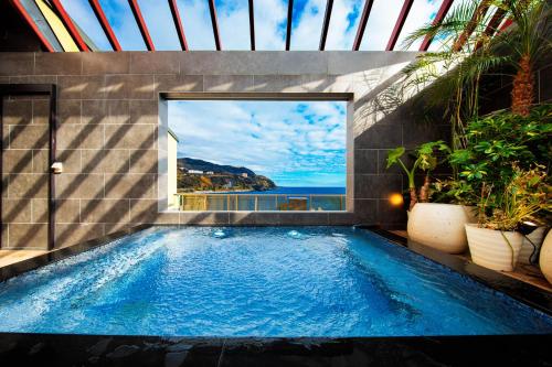 a swimming pool in a house with a view of the ocean at Inatori Akao Hotel in Higashiizu
