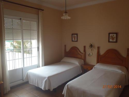 two beds in a bedroom with a window at Casa Rural El Jarral in Jarafuel