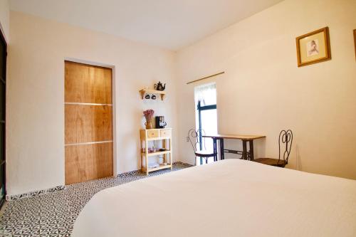 1 dormitorio con cama blanca y mesa en Hermosa Suite Privada en Casa Holística en Cuernavaca