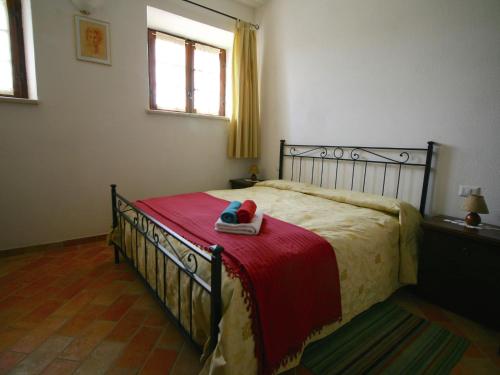 a bedroom with a bed with a red blanket at Vintage Farmhouse with Pool in Asciano in Asciano