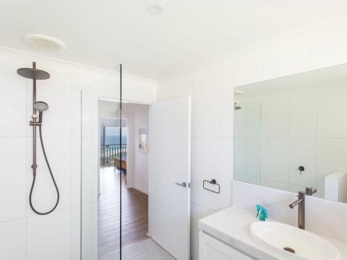 baño blanco con ducha y lavamanos en Aqua Palm with Sweeping One Mile Views en Forster